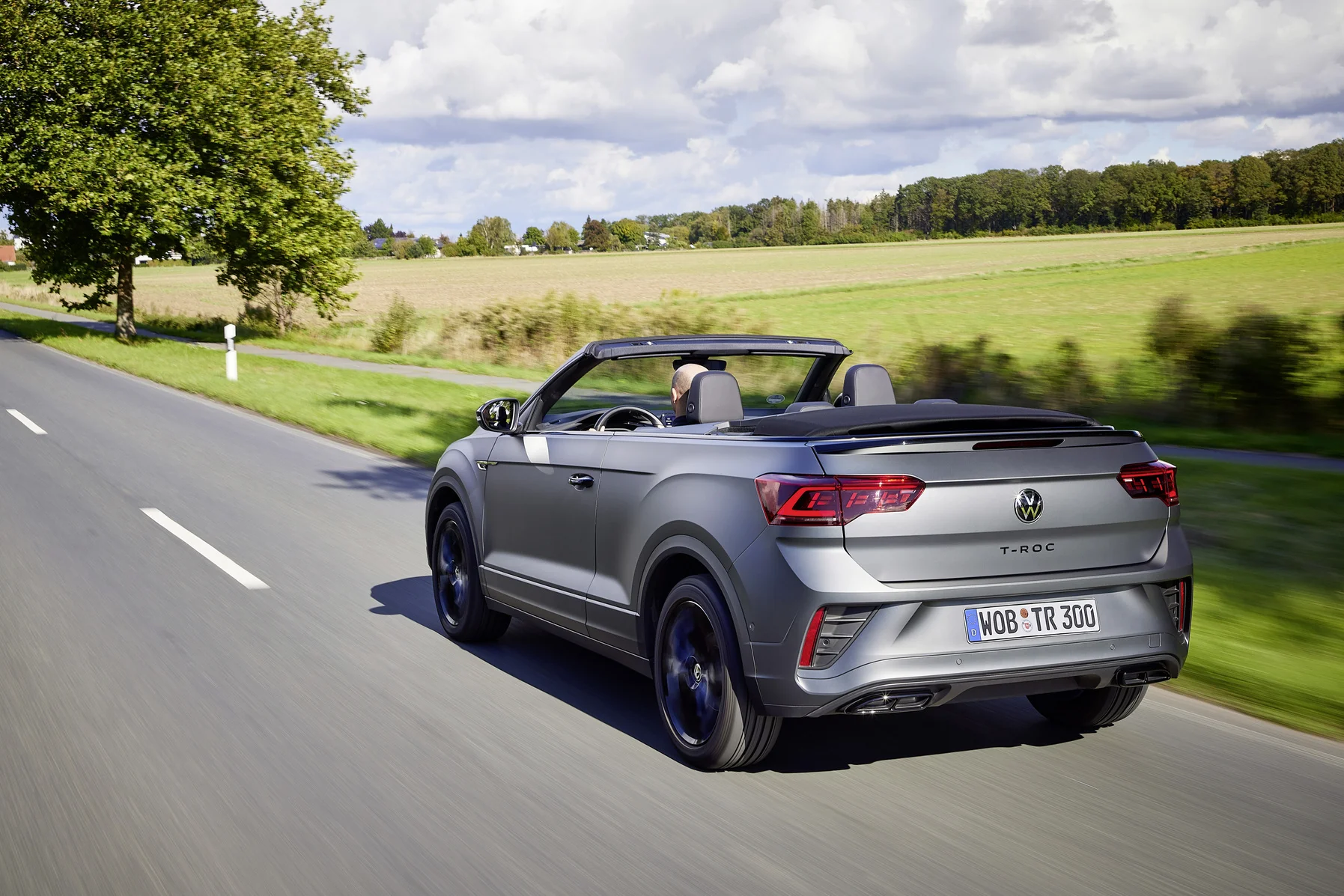 Dynamische Fahraufnahme: der Volkswagen T-Roc Cabriolet mit geöffnetem Dach